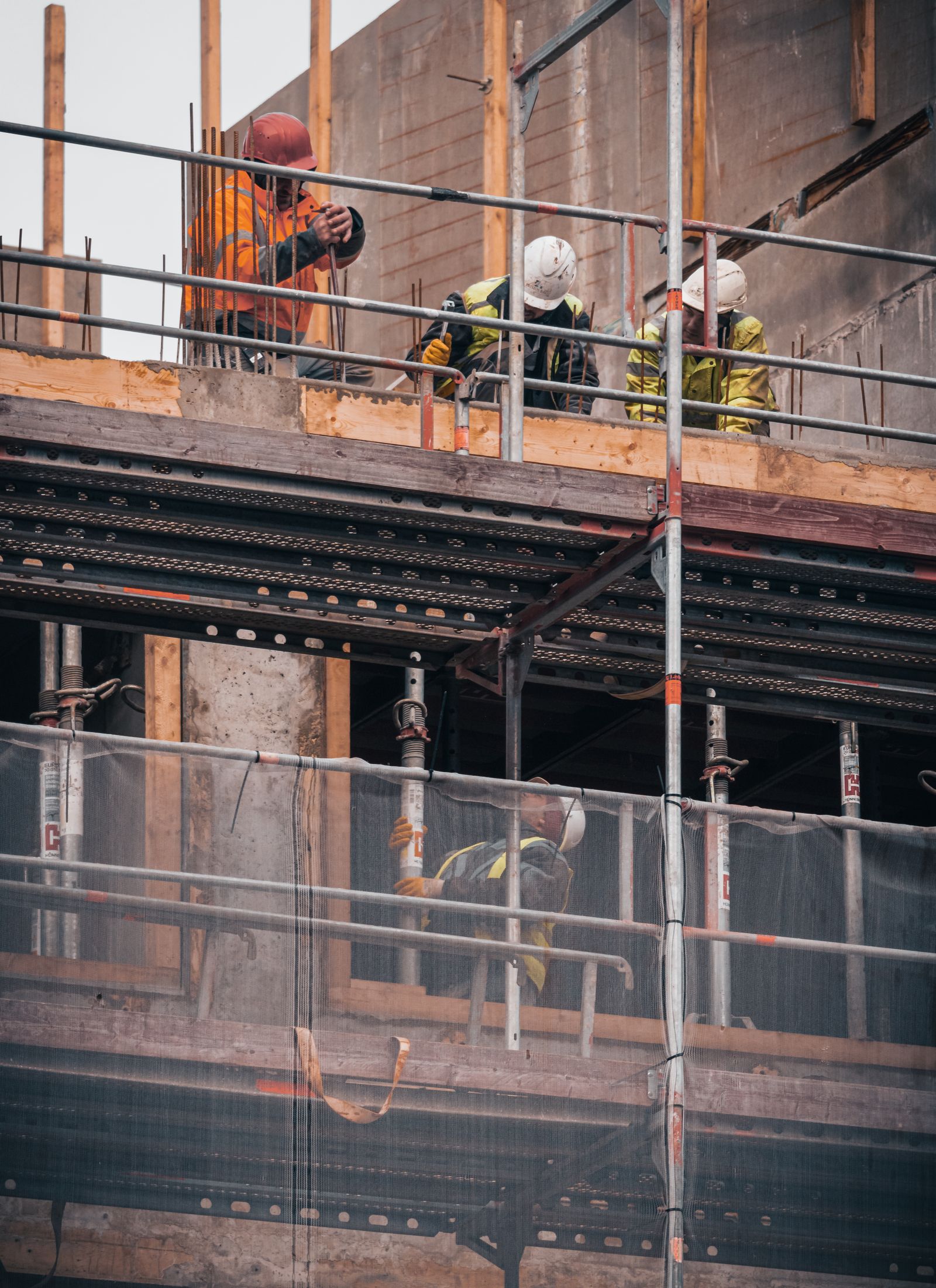 Construction crew in hard hats and hi-vis working on scaffolding