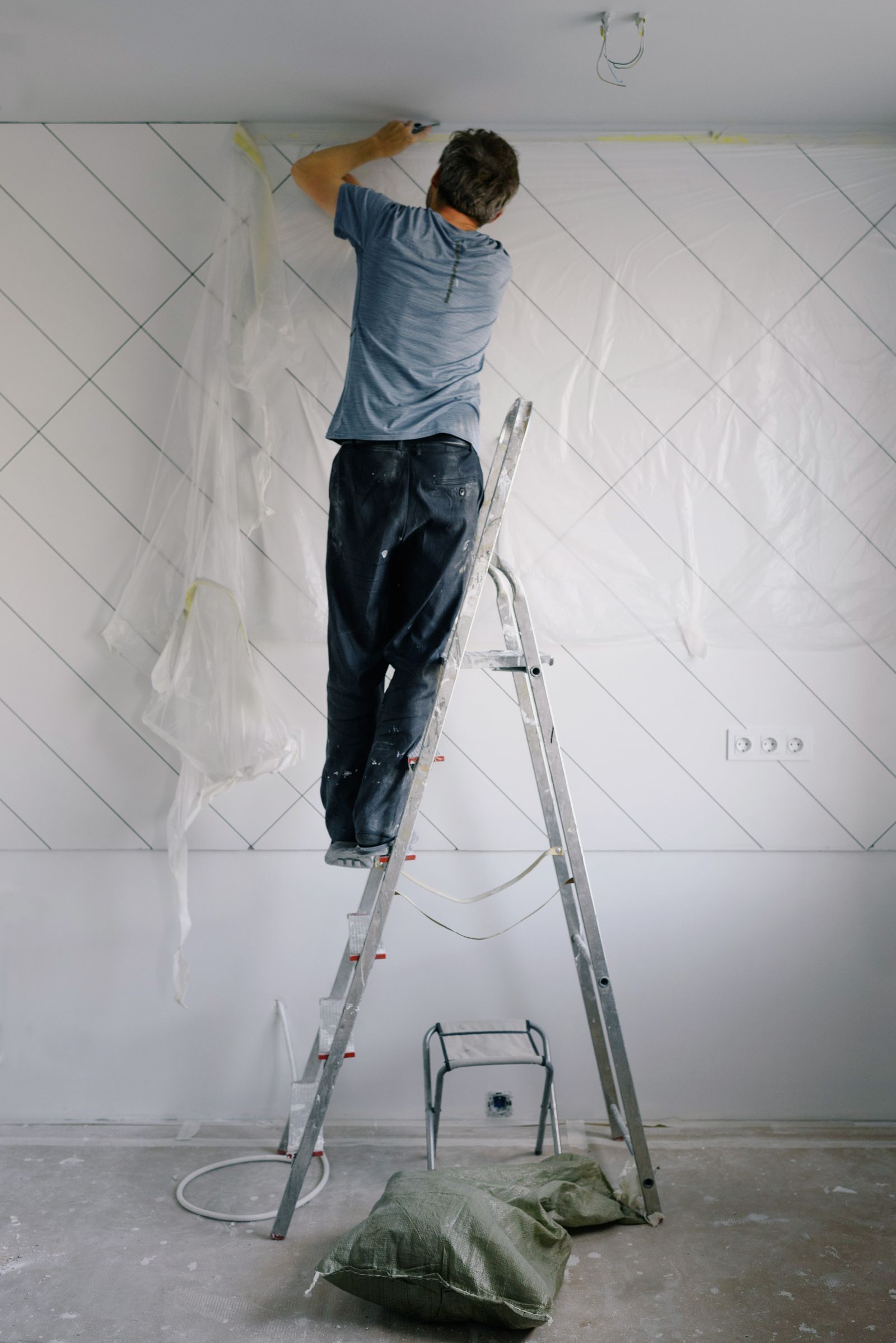 Tradesman on a stepladder carrying out ceiling repairs in a protected room
